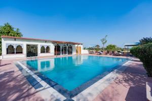 a large swimming pool with a building in the background at Chomu Bagh Hotel & Resorts in Chomu in Jaipur