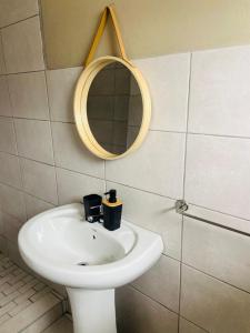 ウムタタにあるSunshine Lodgeの白い洗面台と鏡のあるバスルーム +4枚の写真