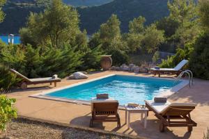 a swimming pool with two lawn chairs and two loungers at Villa Alba in Vathi, Ithaka