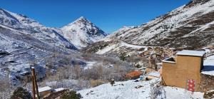 a snow covered mountain with a town and a building at Dar Agourzi Café des Epices in Tacheddirt