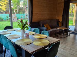 a wooden table with plates and chairs and a couch at KASZUBY Oliwkowy domek Niesiołowice na Kaszubach Balia z Jacuzzi Jeziora lasy in Niesiołowice