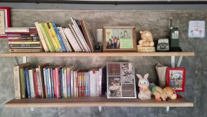 a book shelf with books and stuffed animals on it at บ้านครูเอ๋โฮมสเตย์ Baankruae Homestay 