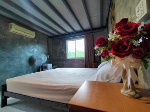 a bedroom with a bed with a vase of roses on a table at บ้านครูเอ๋โฮมสเตย์ Baankruae Homestay 