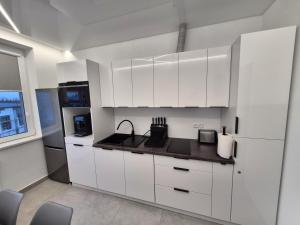 APARTAMENTY Korczaka في مييلتس: مطبخ ابيض مع دواليب بيضاء وثلاجة