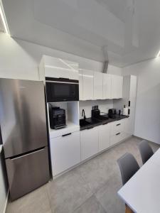 APARTAMENTY Korczaka في مييلتس: مطبخ بخزائن بيضاء وثلاجة من الفولاذ المقاوم للصدأ