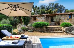 een patio met een parasol en een zwembad bij U Caseddu in Sotta