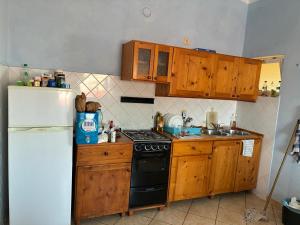 Una cocina con gabinetes de madera y un refrigerador blanco. en A casa do amor, en Vila do Maio 12 fotos más