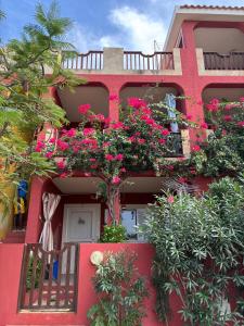 a red building with flowers on the side of it at A casa do amor in Vila do Maio