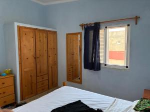 1 dormitorio con 1 cama y 2 armarios de madera en A casa do amor, en Vila do Maio