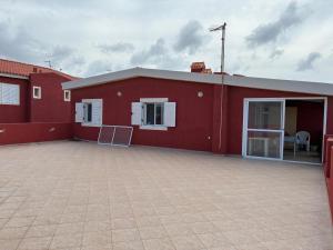 a red building with a large parking lot at A casa do amor in Vila do Maio