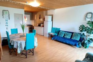 a living room with a table and a blue couch at Maison Datcha Gîte avec jardin et piscine privée in Lavaur
