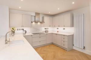 a white kitchen with white cabinets and a sink at Abbotsford House sleeps 8 in York