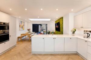 a kitchen with white cabinets and a living room at Abbotsford House sleeps 8 in York +35 photos