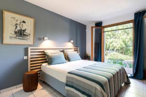 een slaapkamer met een bed en een groot raam bij Villa Baccarat in Porto-Vecchio