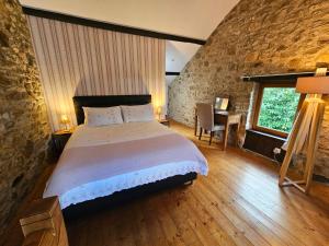 een slaapkamer met een groot bed in een stenen muur bij Le Cosy - Domaine du Vertendre in Saint-Yrieix-la-Perche
