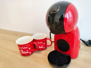 a red coffee maker with two cups on a table at Cuibul Practic in Oradea