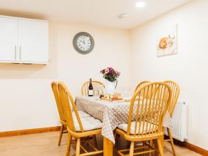 The Barn في Girthon: طاولة طعام مع كراسي وساعة على الحائط