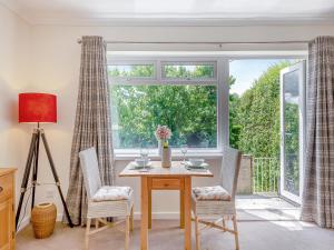 Un comedor con mesa y sillas y una ventana. en Black Hill View, en Manaton
