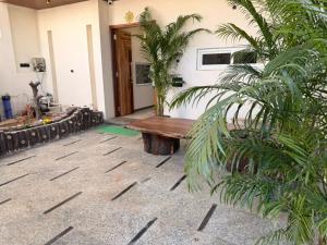 Un banco de madera frente a una casa con palmeras. en Homyana stays, en Jāmb