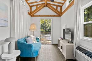 a living room with a blue chair and a tv at Laurel Bush Combo - 6 Waterfront Homes, Fish, Hike, and Mountain Views! in Sylva