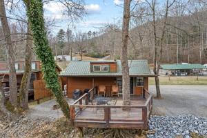 a log cabin with a deck in the woods at Tuck River Magic - 6 Waterfront Homes, Fish, Hike, and Mountain Views! in Dillsboro