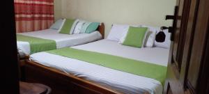 two beds with green and white sheets in a room at Haranya Homestay in Hatton