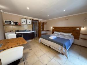 a bedroom with a bed and a kitchen and a table at Campo Base Aparts in El Chalten +25 photos