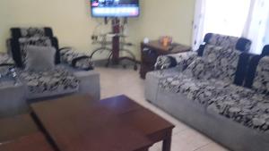 a living room with a couch and a table and a tv at La Hacienda in Nairobi