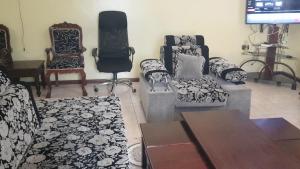 a living room with couches and chairs and a tv at La Hacienda in Nairobi