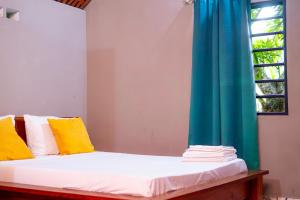 un letto con cuscini gialli e bianchi e una finestra di Le Jardin Arhumatic Sambava a Sambava