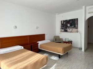Una habitación de hotel con dos camas y una silla. en La Luna Blanca, en Torremolinos 80 fotos más