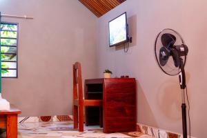 una stanza con un ventilatore, una scrivania e una TV di Le Jardin Arhumatic Sambava a Sambava