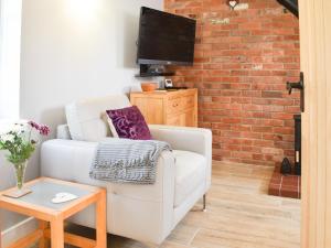 a living room with a white couch and a brick wall at White Heather Barn in Swanwick