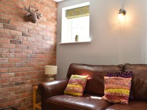a brown leather couch in a room with a brick wall at White Heather Barn in Swanwick