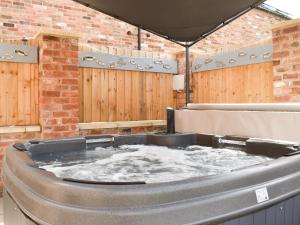 a hot tub in a yard with a wooden fence at White Heather Barn in Swanwick