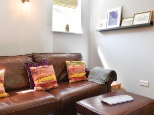 a brown leather couch with colorful pillows on it at White Heather Barn in Swanwick