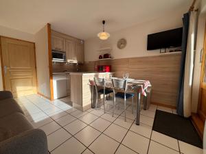 une cuisine avec une table avec des chaises et une cuisine avec une cuisine dans l'établissement Résidence Atrey 103 Clés Blanches Courchevel, à Courchevel 10 autres photos