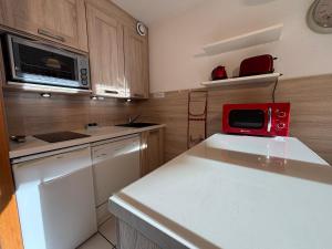 une cuisine avec un micro-ondes rouge sur un comptoir dans l'établissement Résidence Atrey 103 Clés Blanches Courchevel, à Courchevel