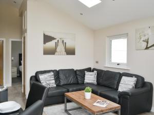 a living room with a black couch and a table at Little Fawn in Otterburn
