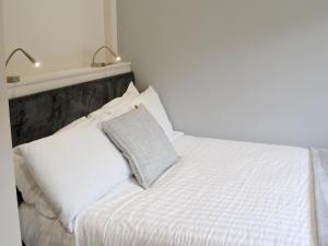 a white bed with two lamps on top of it at Little Fawn in Otterburn +3 photos