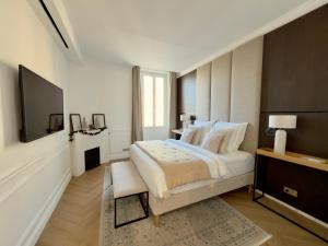 een witte slaapkamer met een groot bed en een tv bij A 2 pas de la croisette in Cannes