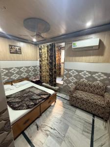een slaapkamer met een bed en een bank erin bij Hotel Aditya Sheraton in Haridwār