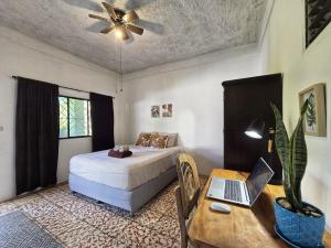een slaapkamer met een bed en een bureau met een laptop bij 4 Amigos El Zonte in ChiltiupÃ¡n