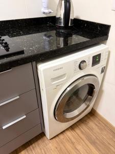 a white washing machine in a kitchen with a black counter at Apartamento 1 quarto, com garagem no centro próximo Hospital de Caridade in Santa Maria