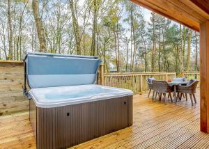 a hot tub on a wooden deck with a table at Elton Furze Retreats in Haddon