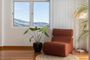 een woonkamer met een stoel en een plant bij Casa Tabaibo by An Island Apart in Funchal