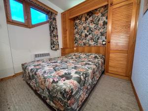 ein Schlafzimmer mit einem Bett mit geblümter Tagesdecke in der Unterkunft Résidence Atrey 205 Clés Blanches Courchevel in Courchevel