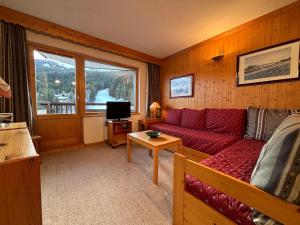 ein Wohnzimmer mit einem roten Sofa und einem Fenster in der Unterkunft Résidence Atrey 205 Clés Blanches Courchevel in Courchevel