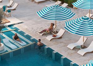 a group of people sitting in chairs and umbrellas by a pool at Desert Rose in Hurghada