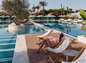 a woman sitting in chairs by the pool at a resort at Desert Rose in Hurghada